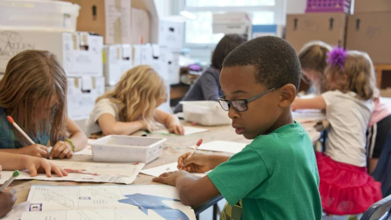 Eine Gruppe von Schulkindern zeichnet konzentriert mit Stift und Papier an einem großen Tisch.