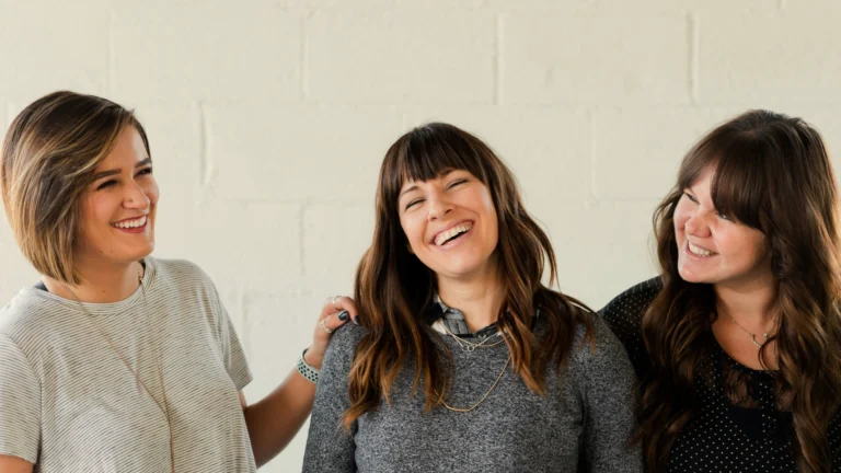 Drei Frauen vor einer weißen Wand. Sie lachen und scheinen sich gut zu verstehen.