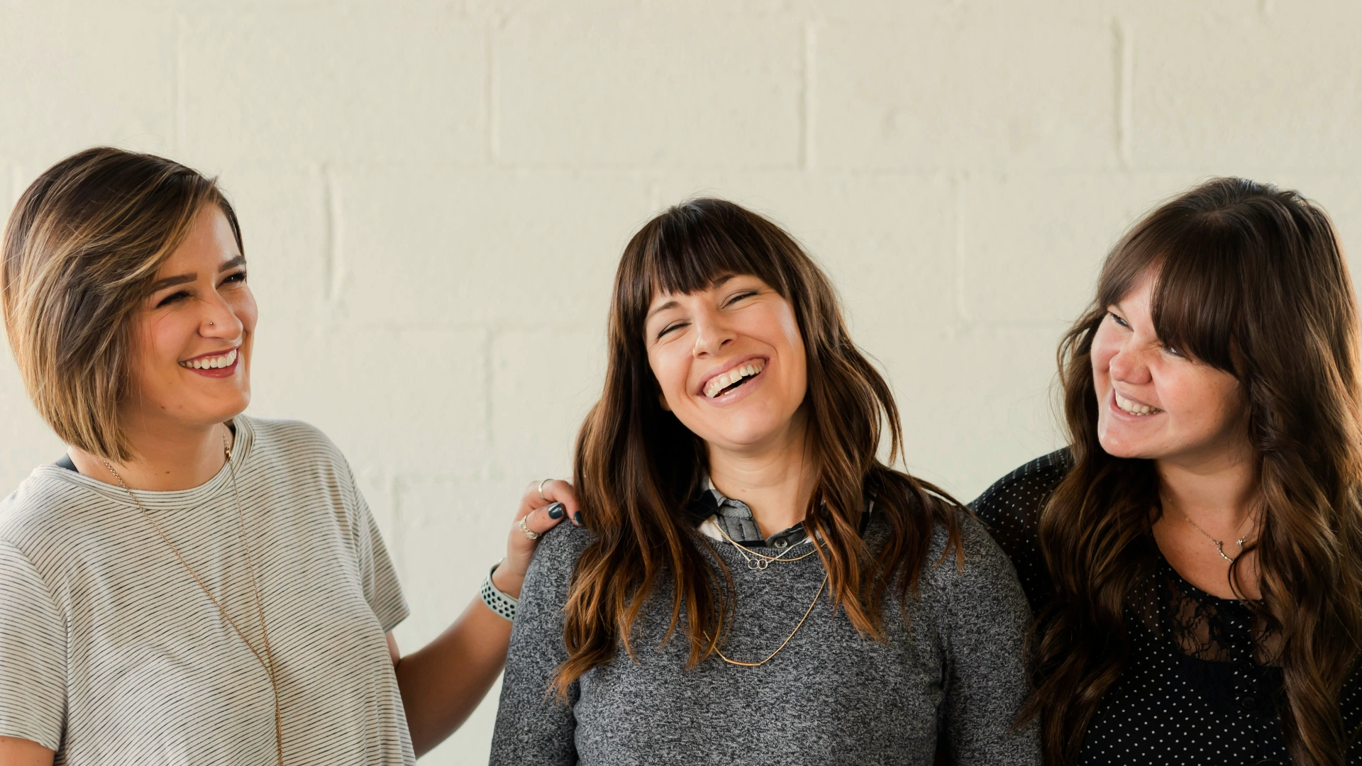 Drei Frauen vor einer weißen Wand. Sie lachen und scheinen sich gut zu verstehen.