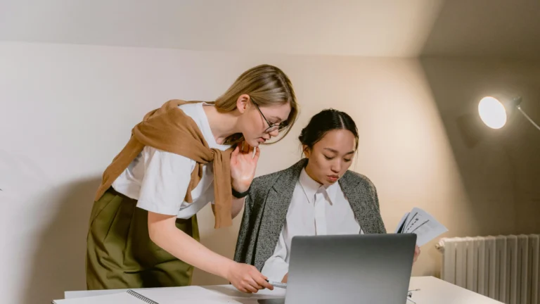 Zwei Junge Frauen beugen sich geschäftig und konzentriert über einen Laptop.